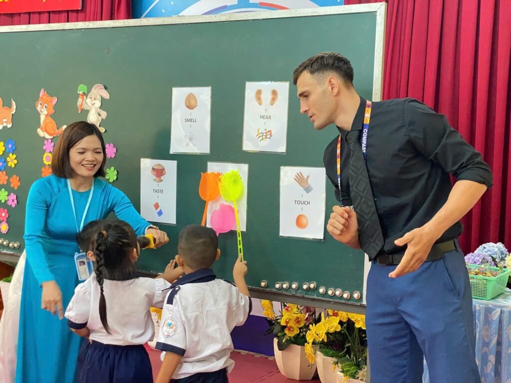 South African teacher leading an English lesson with primary school students in Vietnam